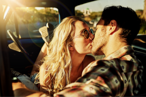 young couple kissing at sunset in the car.