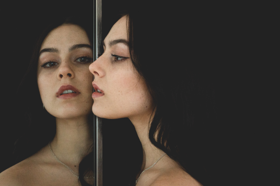 A woman looks in the mirror and thinks about what does it mean to love yourself