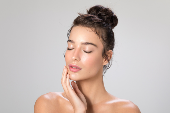 A 27-year-old woman with delicate skin caresses her face.