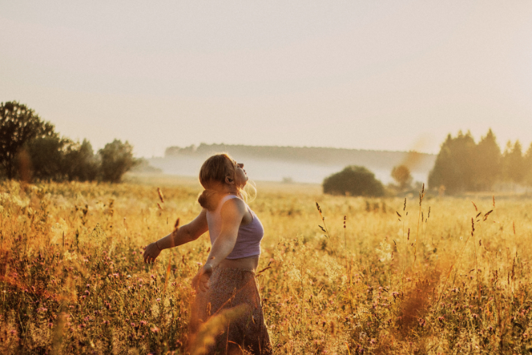 A woman on the grassland embraces her inner child with love and healing, finding the potential for change