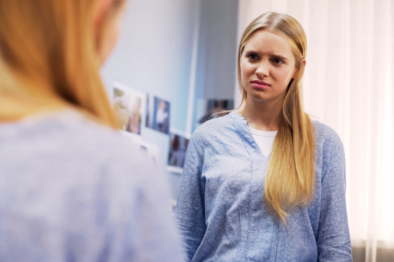 A female teenager is looking at herself in the mirror and asking How to Overcome Self-Doubt