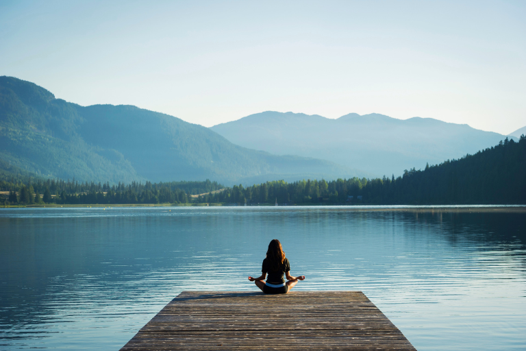 A woman practicing cultivate self-care by the lake